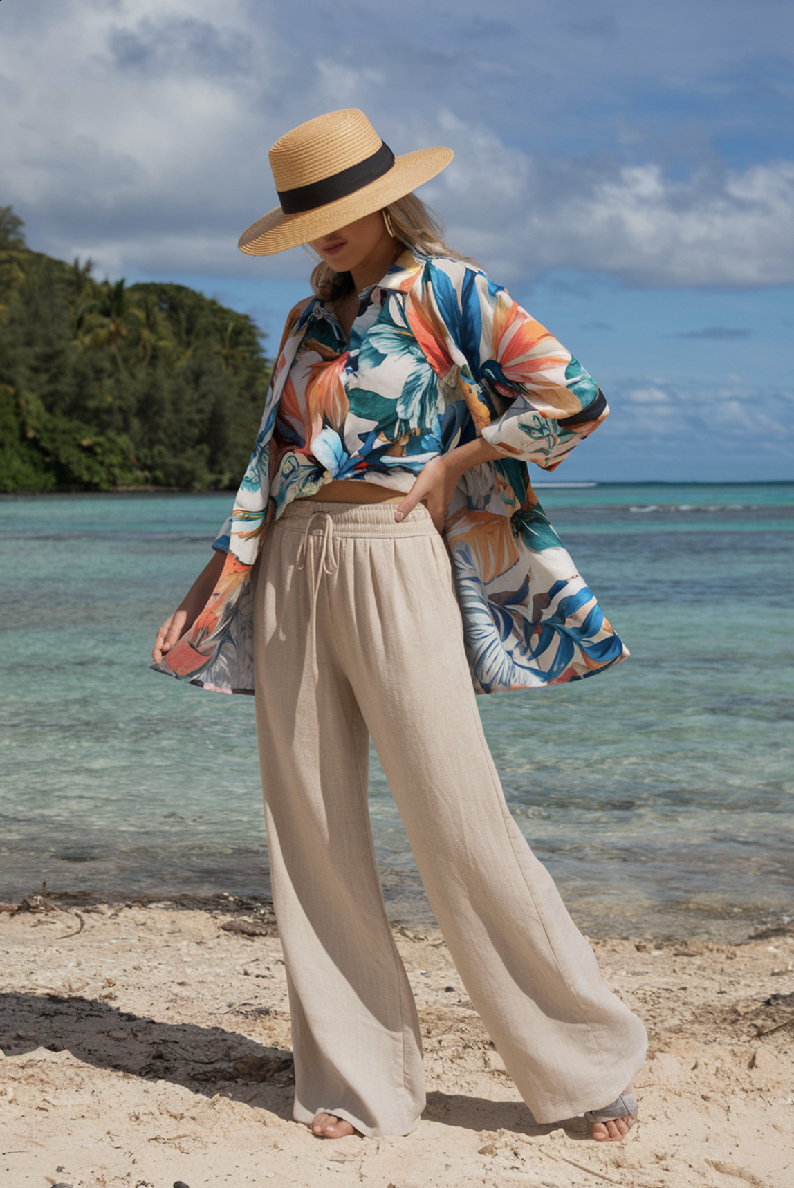 beige linen pants with a tropical floral shirt and straw hat on a beach